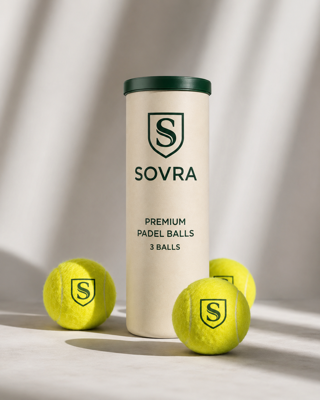 Tubo de pelotas Sovra junto a dos pelotas de pádel sobre una superficie clara con luz suave.